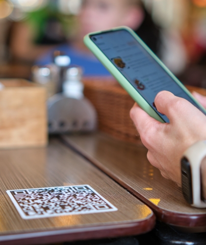 A consumer using a smart phone to scan a table QR code to open an app to order table service - using Fast Charger to keep there battery topped up and them connected