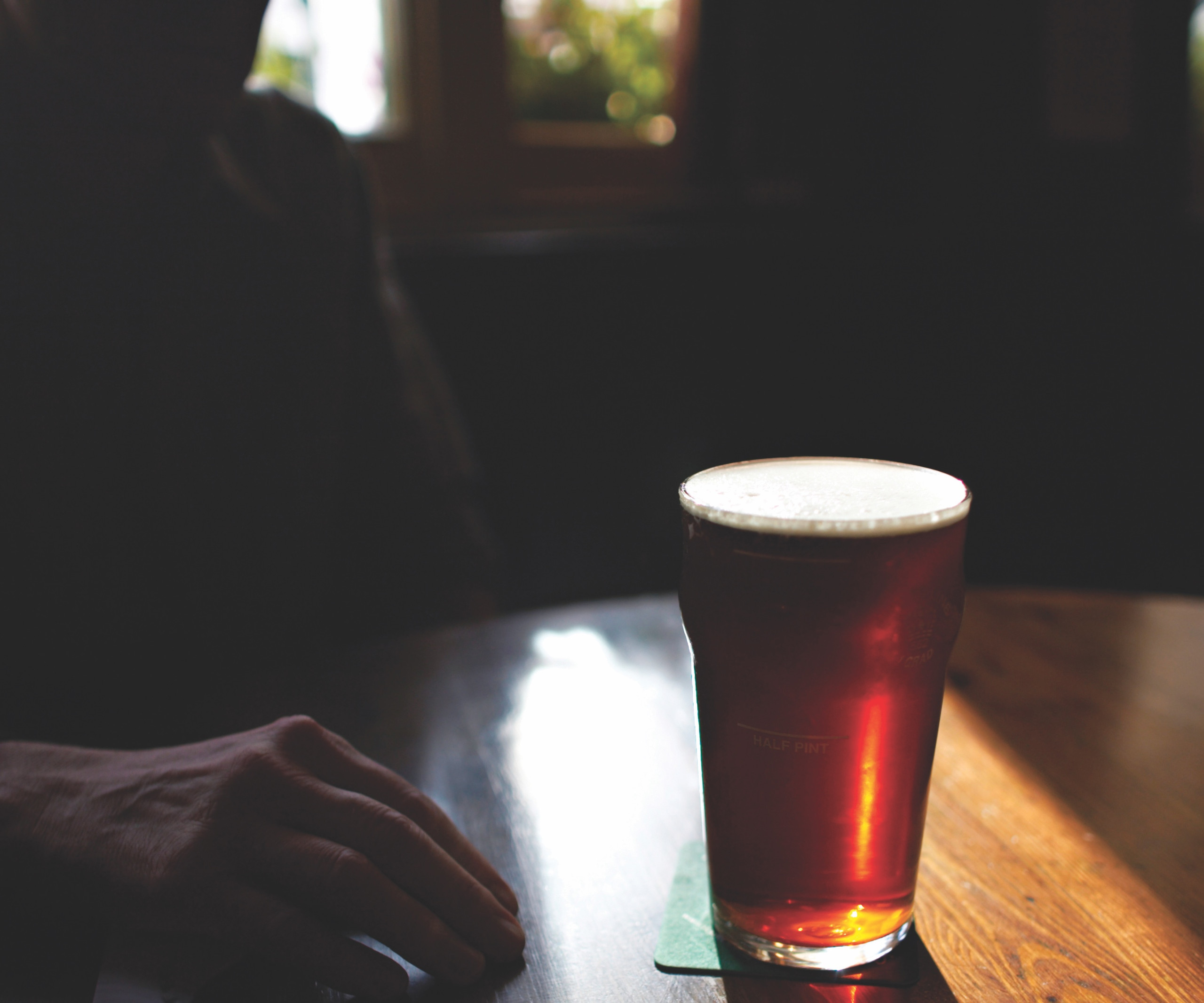 A man in shadow with a pint of beer on a table