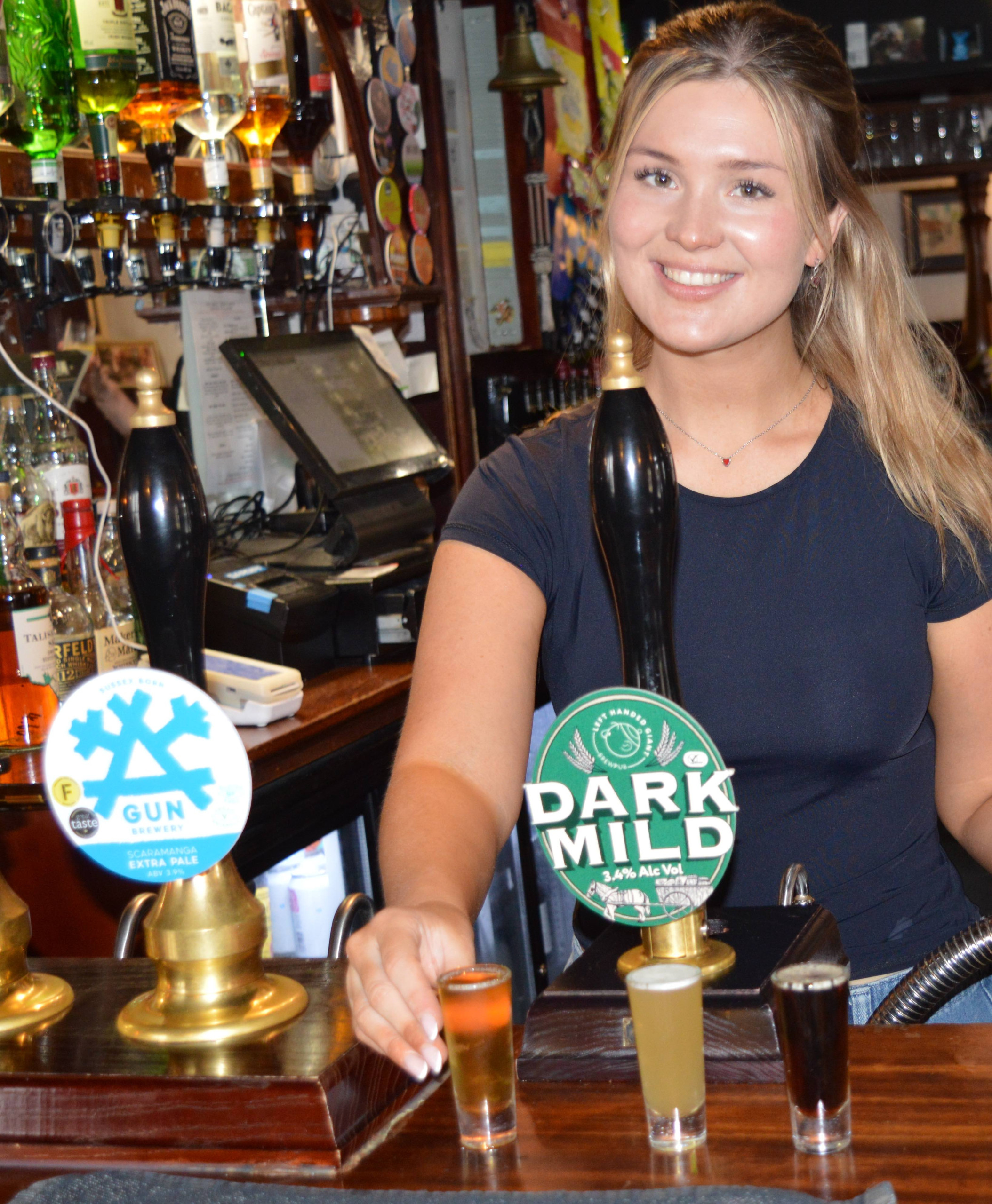 A female bartender offering beer samples